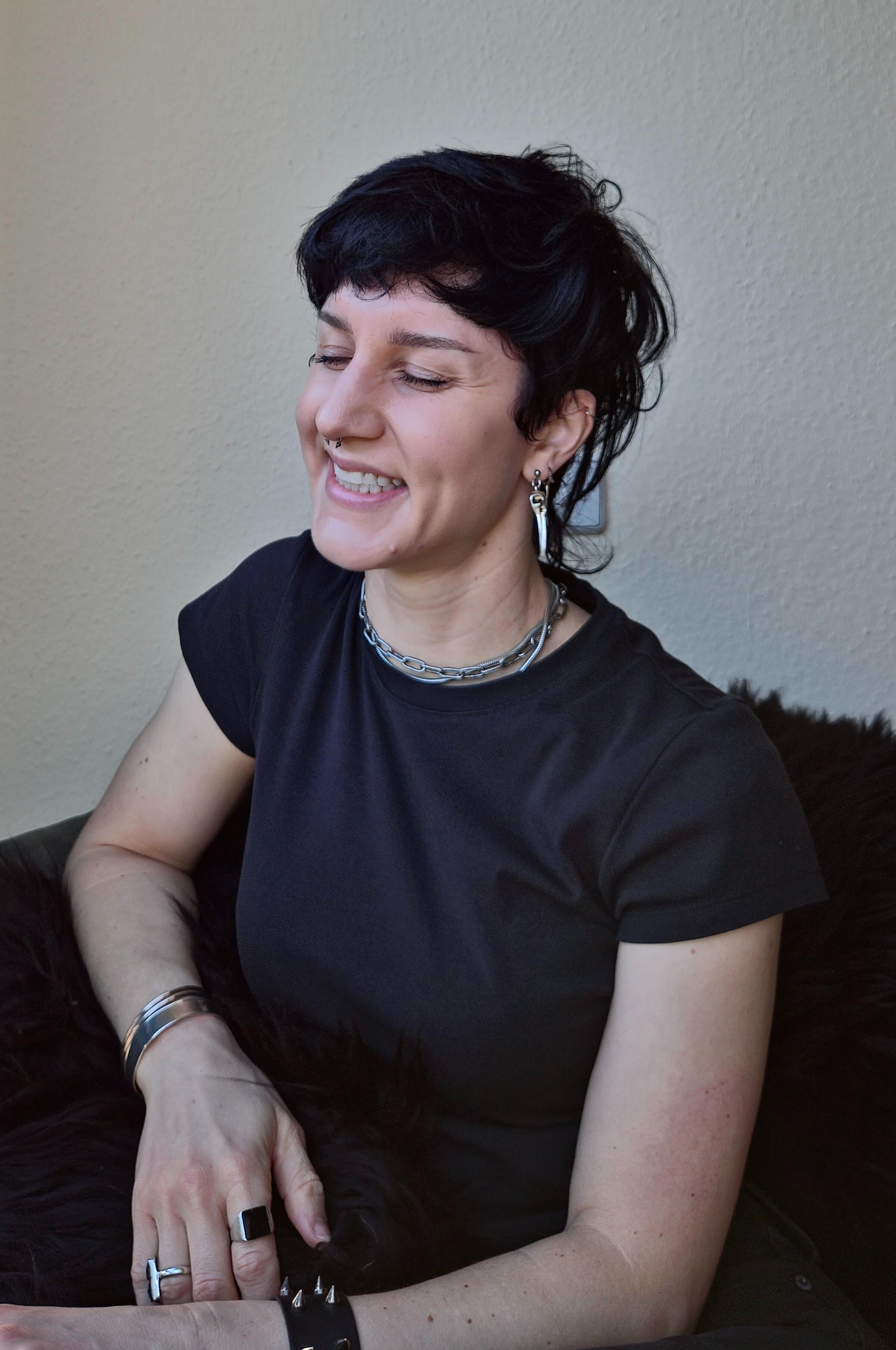 Molly Daszuta, LCSW - psychological counseling, relational therapy, clinical social work Molly Daszuta, laughing on their comfy couch, in Jena, Germany.